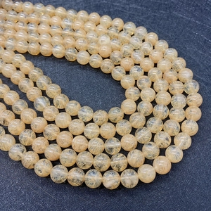 Macro detail of natural golden rutilated quartz beads showing internal needle inclusions