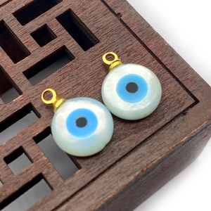 Macro view of natural shell evil eye pendants with gold bail on a dark wooden background