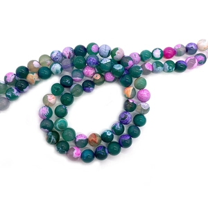 Green and purple dragon vein agate beads arranged in a spiral for DIY jewelry making