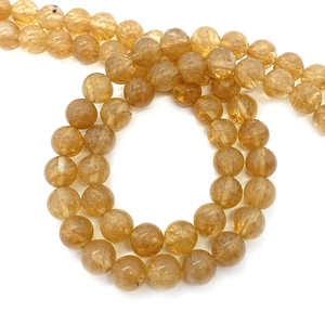 Translucent golden round natural stone beads in a spiral arrangement on white background