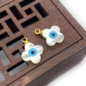 Detail of flower-shaped mother of pearl pendants with blue evil eye and gold loops