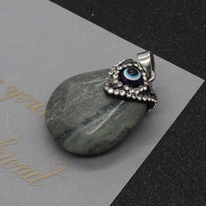 Macro-opname van de hartvormige boze oog hanger met strass op een grijze kiezelsteen