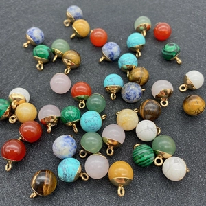 Macro-opname van kleurrijke ronde hangers van natuursteen met gouden metalen oogjes op grijs