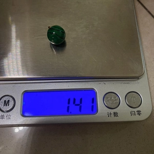 Macro-opname van 1,41g ronde malachiet hanger met zilveren oogje op digitale weegschaal