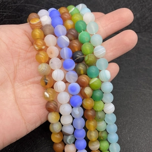 Close-up of matte natural silk agate beads with colorful round textures for DIY jewelry