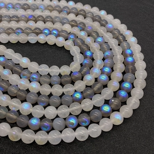 Macro detail of moonstone round beads showing brilliant blue iridescence on black pad
