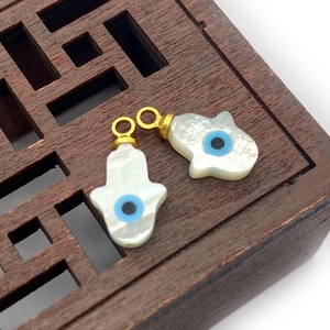 Detailed view of iridescent shell Hamsa Hand pendants with blue evil eye inlay details