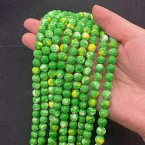 Detailansicht der grün-gelben Marmormuster-Steinperlen für DIY-Schmuck in der Hand gehalten