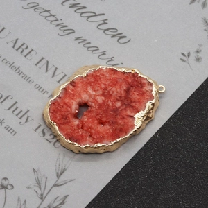 Macro detail of natural red crystal druzy pendant with gold electroplated edges