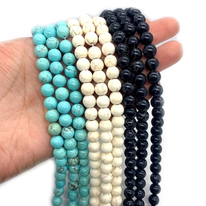 Hand holding strands of turquoise and natural stone round beads for DIY jewelry making