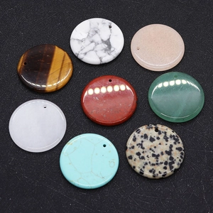 Flat lay of multiple 30mm natural stone round charms with pre-drilled holes for DIY jewelry