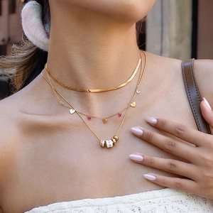 Close-up of layered gold necklaces with ruby heart pendant and enamel star moon charms