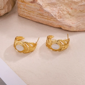 Détail de boucles d'oreilles plume dorées vintage avec pierres blanches ovales