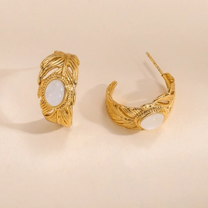 Détail macro de boucles d'oreilles feuille dorées avec incrustation d'opale translucide