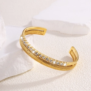 Detailed view of gold titanium steel open bangle with arrow pattern and paved crystals