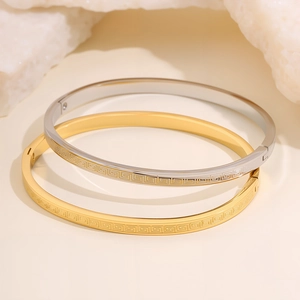 Set of gold and silver titanium steel bangles with Greek key pattern and hinge closure