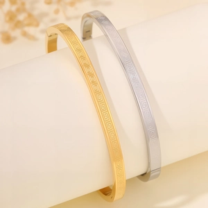 Close-up of gold and silver titanium steel bangles with Greek key pattern engraving