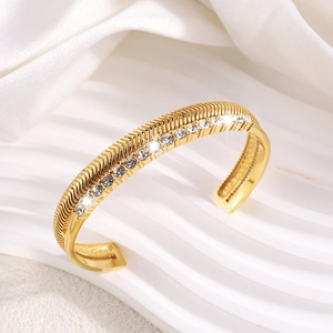 Close-up of golden herringbone engraved cuff bracelet with sparkling crystal inlay