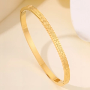 Detail view of gold-plated stainless steel bangle with Greek meander pattern engraving