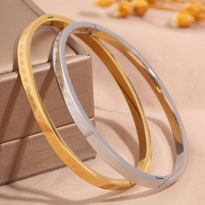 Detail view of gold and silver stainless steel bangles with Greek Key pattern engraving