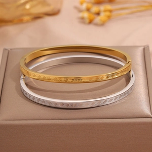 Detail view of gold and silver titanium steel bangles with Greek Key engraving patterns