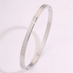 Detail of silver bangle showing classic Greek key geometric patterns and polished finish
