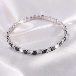Detalle macro de pulsera tenis plateada con piedras negras y blancas brillantes alternas
