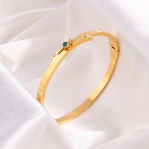 Detailed macro view of gold plated titanium bangle with emerald stone and hinge closure