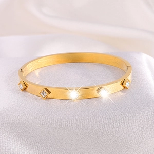 Bracelet jonc en acier inoxydable doré avec cristaux carrés sur fond de soie blanche
