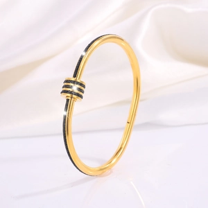 Close-up of golden titanium steel bracelet with black rhinestone cylinder on silk background
