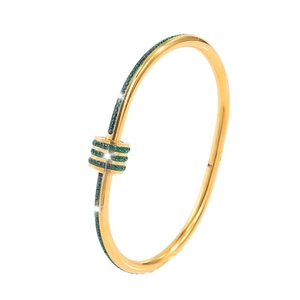 Polished gold titanium bangle featuring T-shaped ends with emerald green pavé crystals