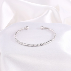 Detalle del brazalete de acero inoxidable trenzado con cuentas de metal pulido