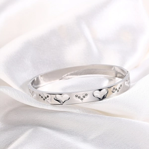 Macro detail of silver heart hollow bracelet with pavé rhinestones on silk