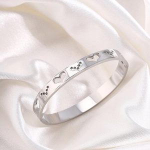 Detail of silver hollow heart bangle with small white rhinestones on silk fabric