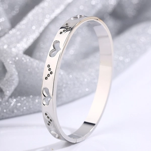 Macro detail of stainless steel heart bangle with black stones on glitter background