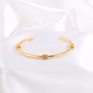 Detalle de una pulsera dorada con tres elegantes detalles decorativos trenzados