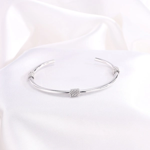 Primer plano de un brazalete de acero inoxidable plateado con textura de espiral