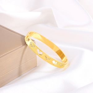 Detailed macro of gold heart bangle with sparkling rhinestones on luxury silk fabric