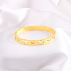 Detail of gold heart hollow bangle with diamond inlay on a white silk background