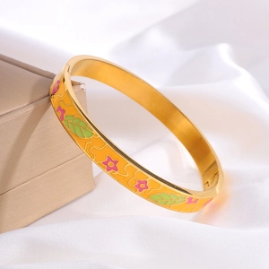 Detail van een gouden emaille armband met roze bloempatronen op een witte zijden achtergrond