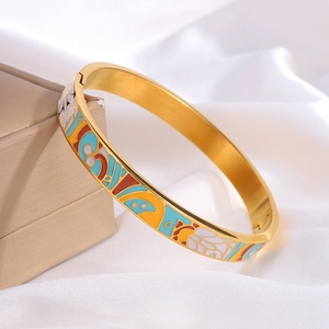 Detail van een vintage gouden emaille armband met geometrische patronen op witte zijde