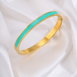 Detailopname van gouden titanium armband met muntgroen email op wit satijnen stof
