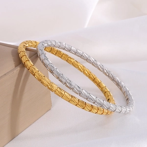 Elegant gold and silver stainless steel bangles with woven texture on white silk backdrop