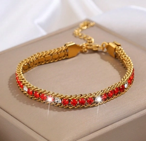 Dettaglio macro del bracciale a catena cubana dorata con zirconi rossi e bianchi
