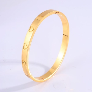 Polished golden titanium steel oval bangle with engraved hollow heart patterns