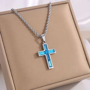 Makroaufnahme einer silbernen Kordelkette mit himmelblauem Kristallkreuz-Anhänger