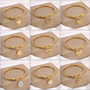 Gold twisted wire bracelets with various luxury heart and flower charms set on display