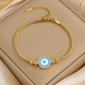 Macro detail of gold-plated stainless steel Evil Eye pendant on a snake chain bracelet