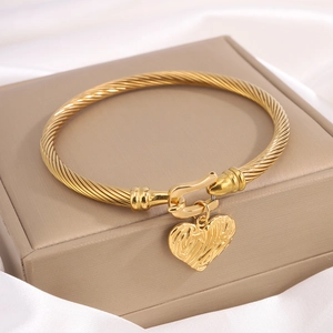 Golden twisted rope titanium steel bracelet with a textured heart charm on silk