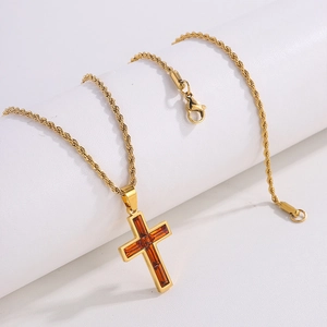 Nahaufnahme der goldenen Kordelkette mit Kreuzanhänger und orangem Zirkonia